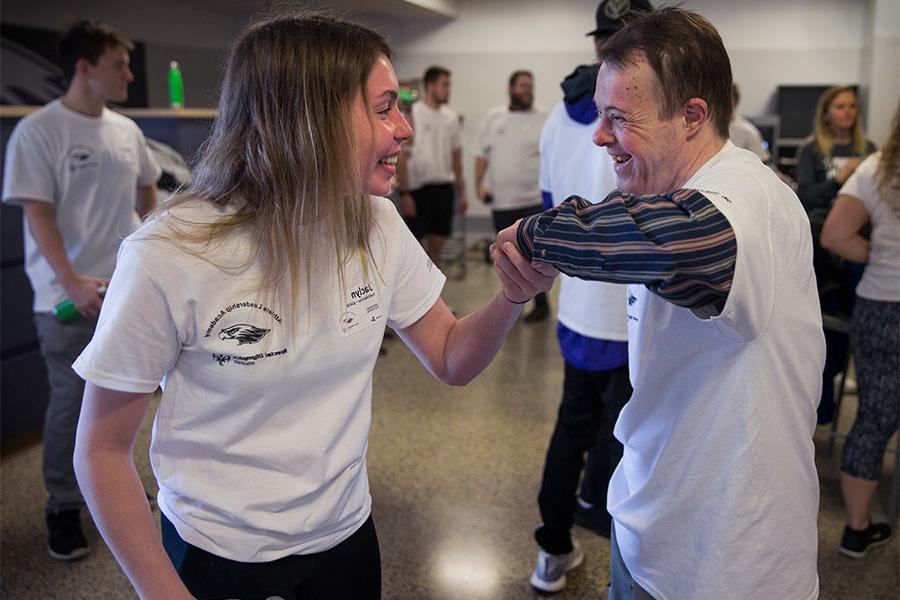 A 足彩平台 student and a person with a disability smile at each other.