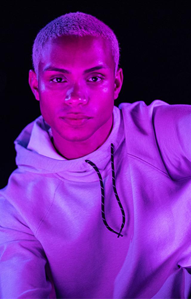 Young man reading tablet in purple light for online college class